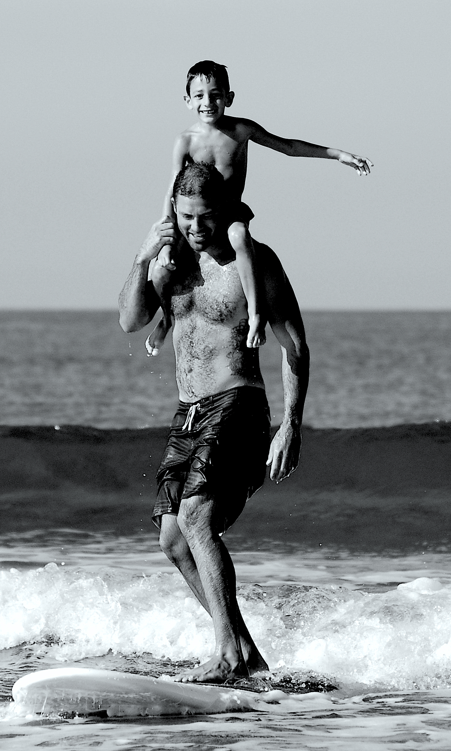 Père surfe avec fils sur le dos