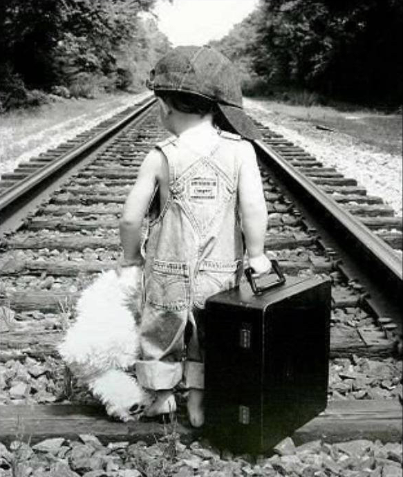 Enfant avec valise sur chemin de fer