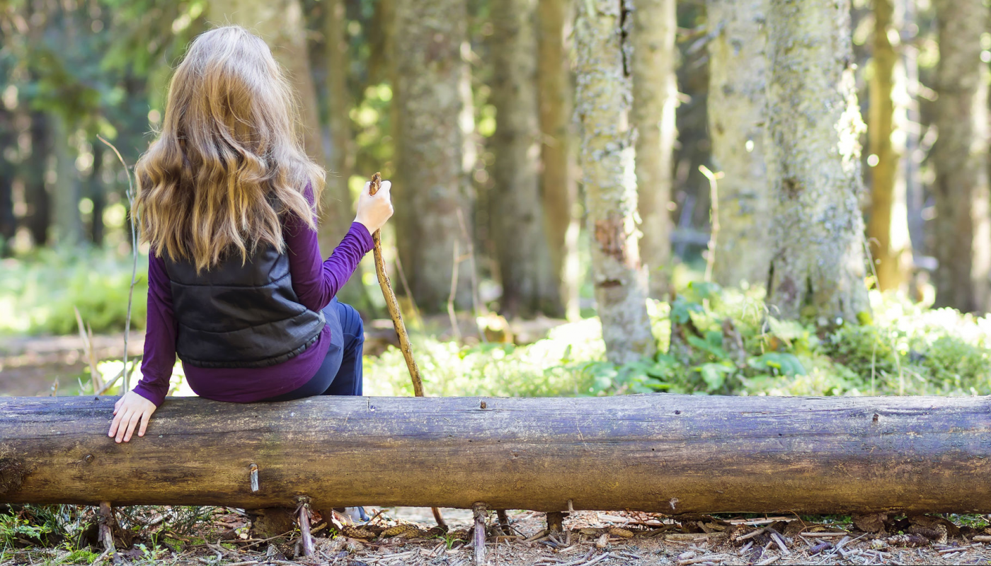 Petite fille assise sur un tronc couché Petite fille assise sur un tronc